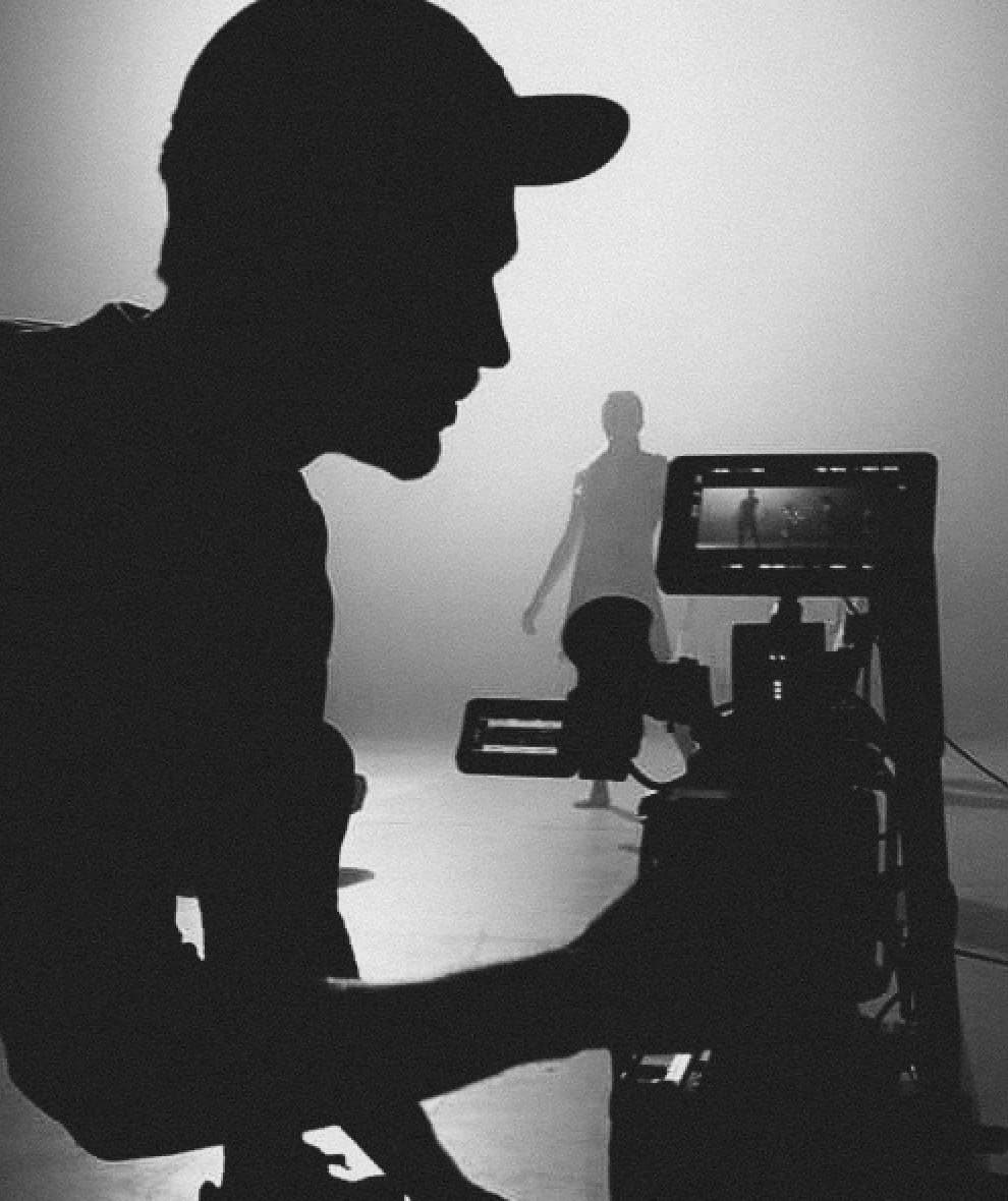 Photograph of a man filming behind a camera.